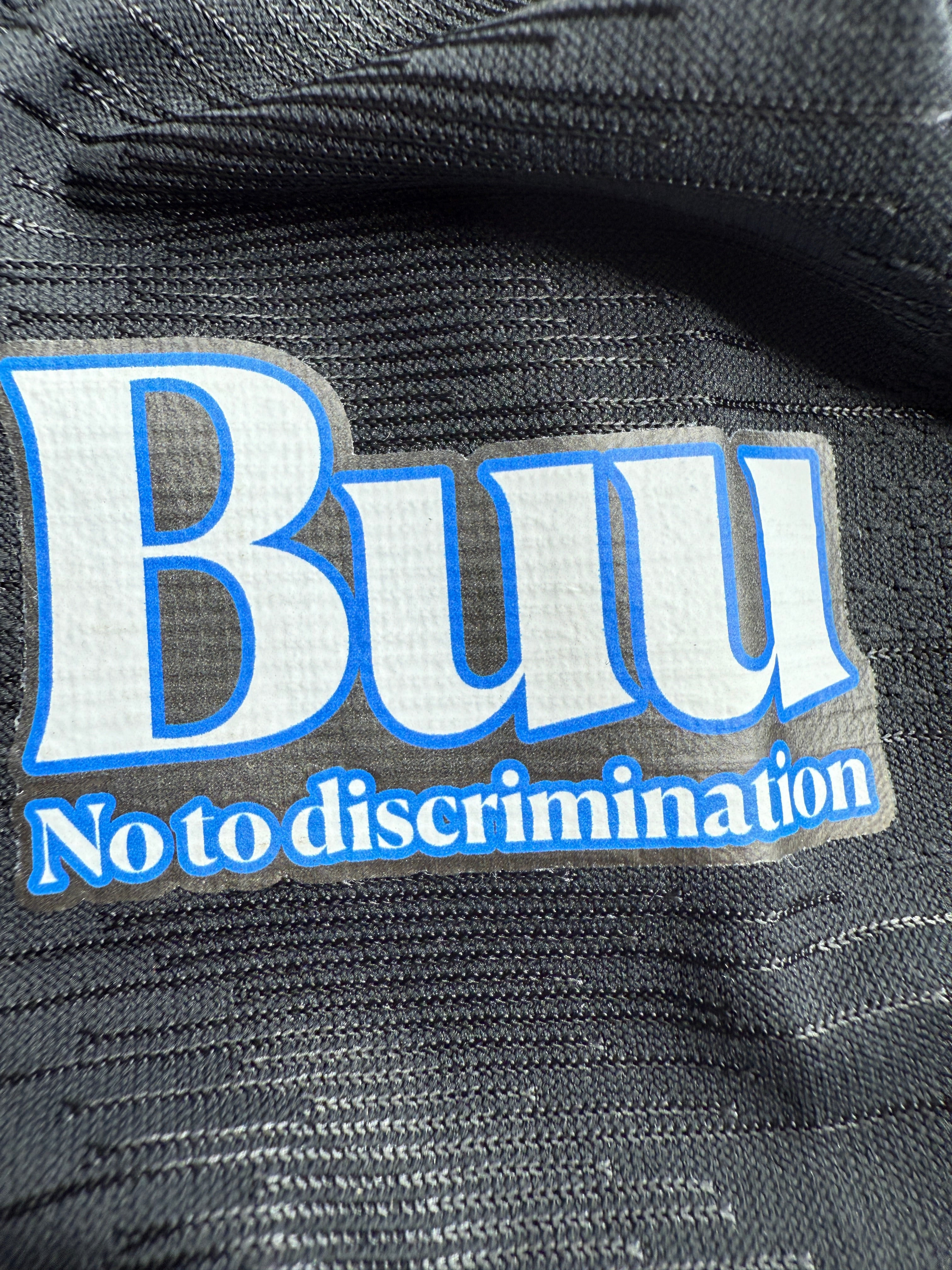 Close-up of a patch on a garment with text 'BUII' and 'No to discrimination'.