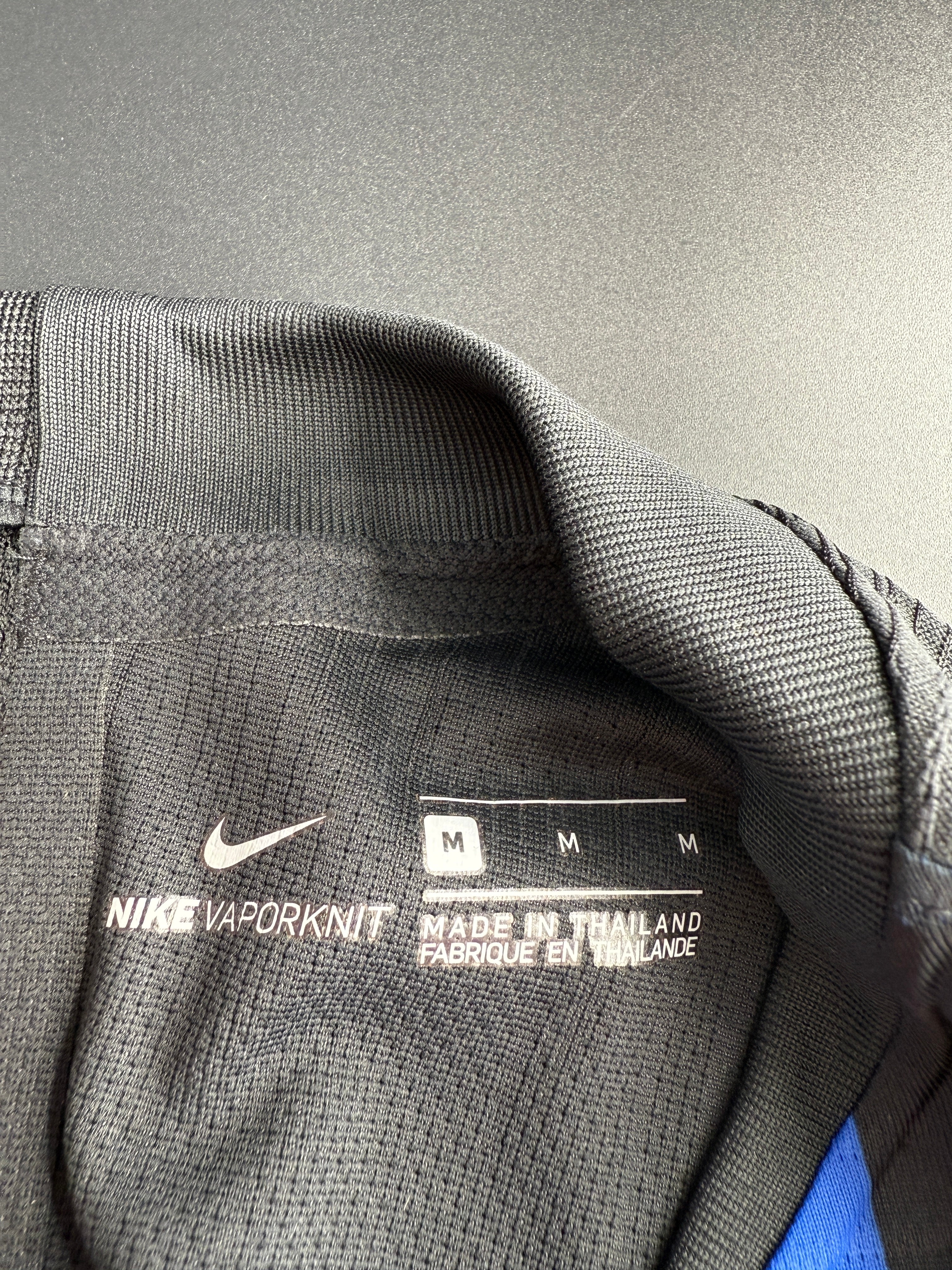 Close-up of gray athletic jacket with fabric label and logo.