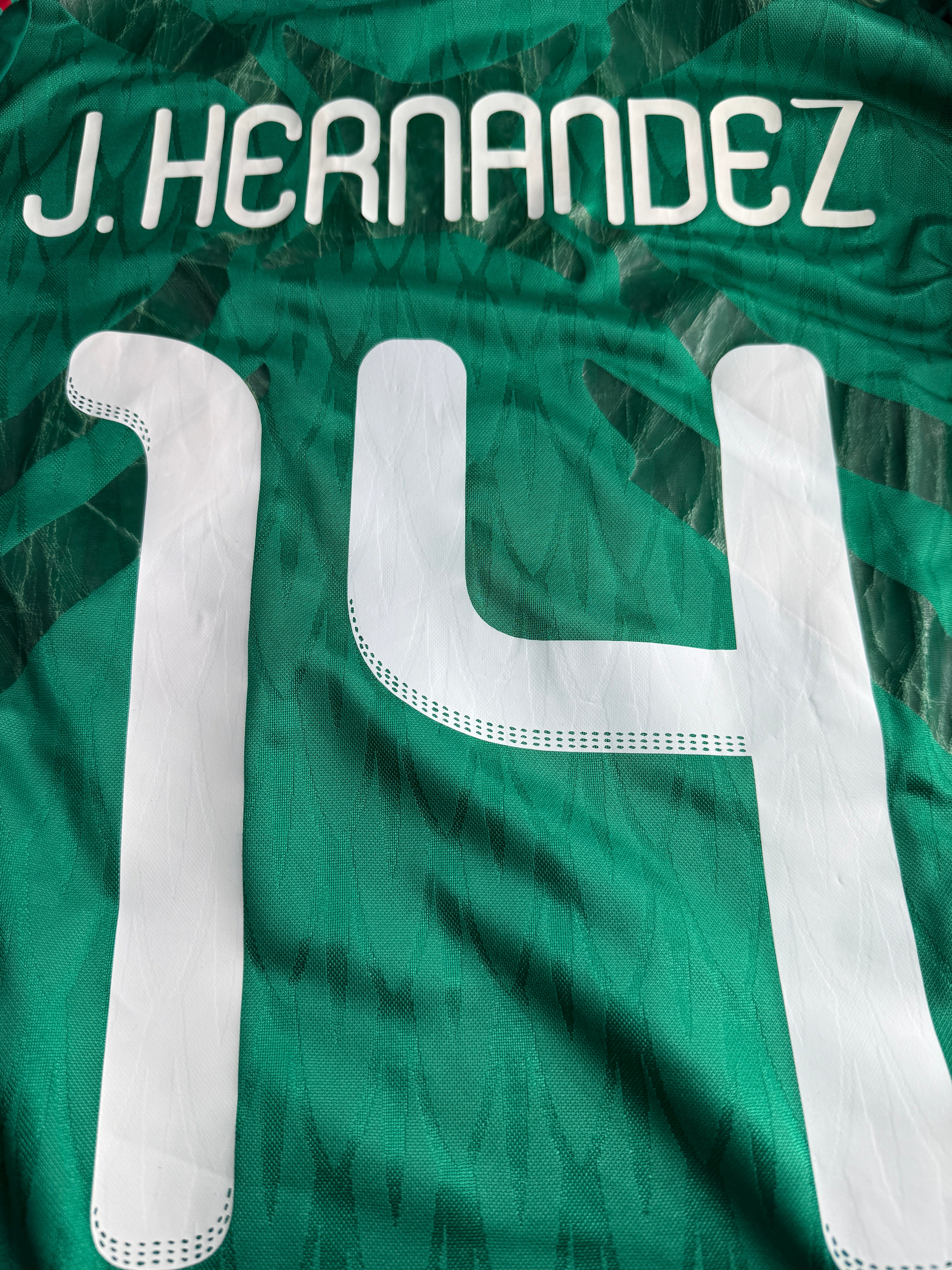 Close-up of a green sports jersey with white lettering and numbers.