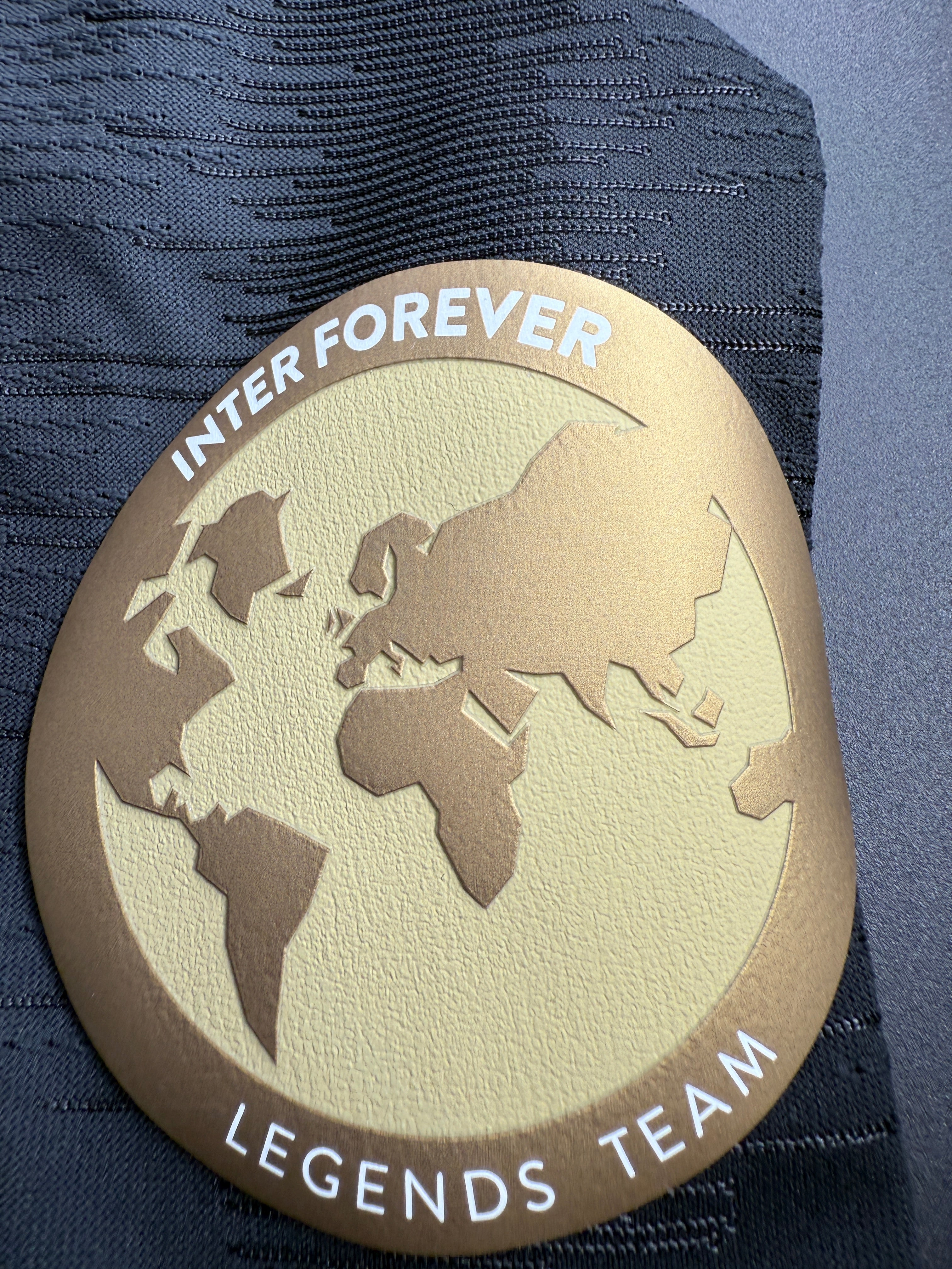 Round emblem with world map and text on textured surface