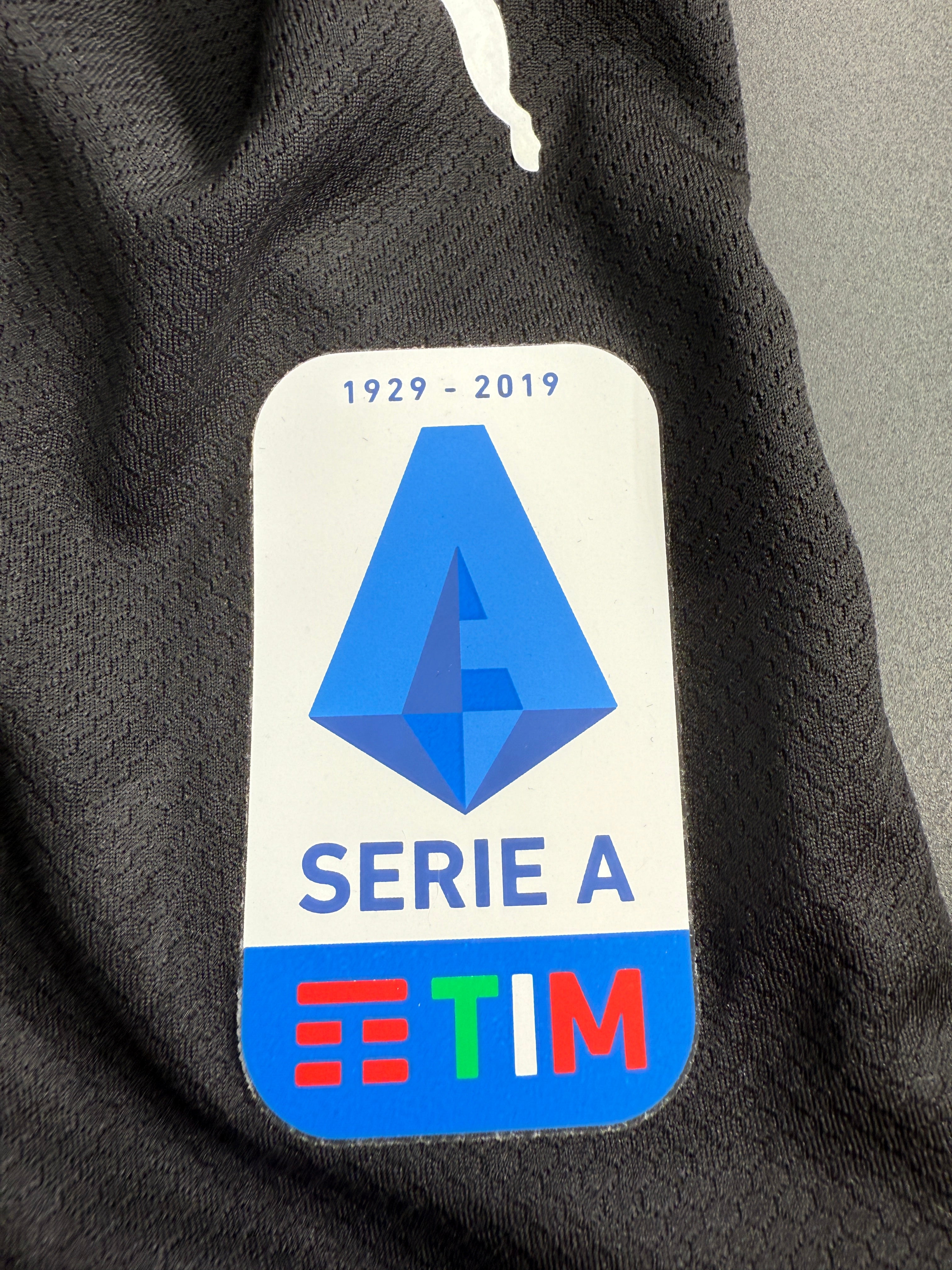 Close-up of a sports jersey patch with 'Serie A' and 'Etim' logos.