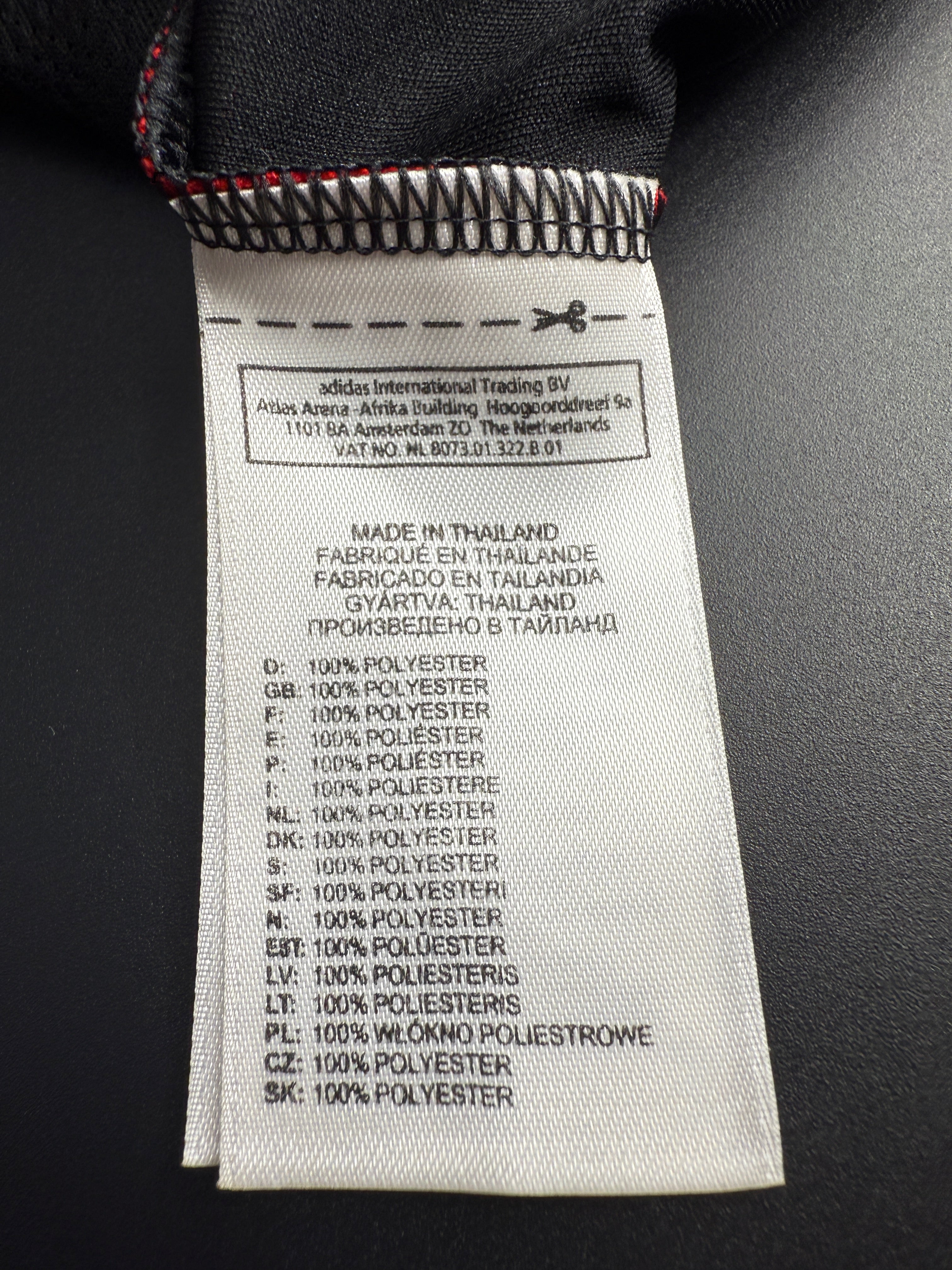 Close-up of fabric label with text and barcode on a black garment.