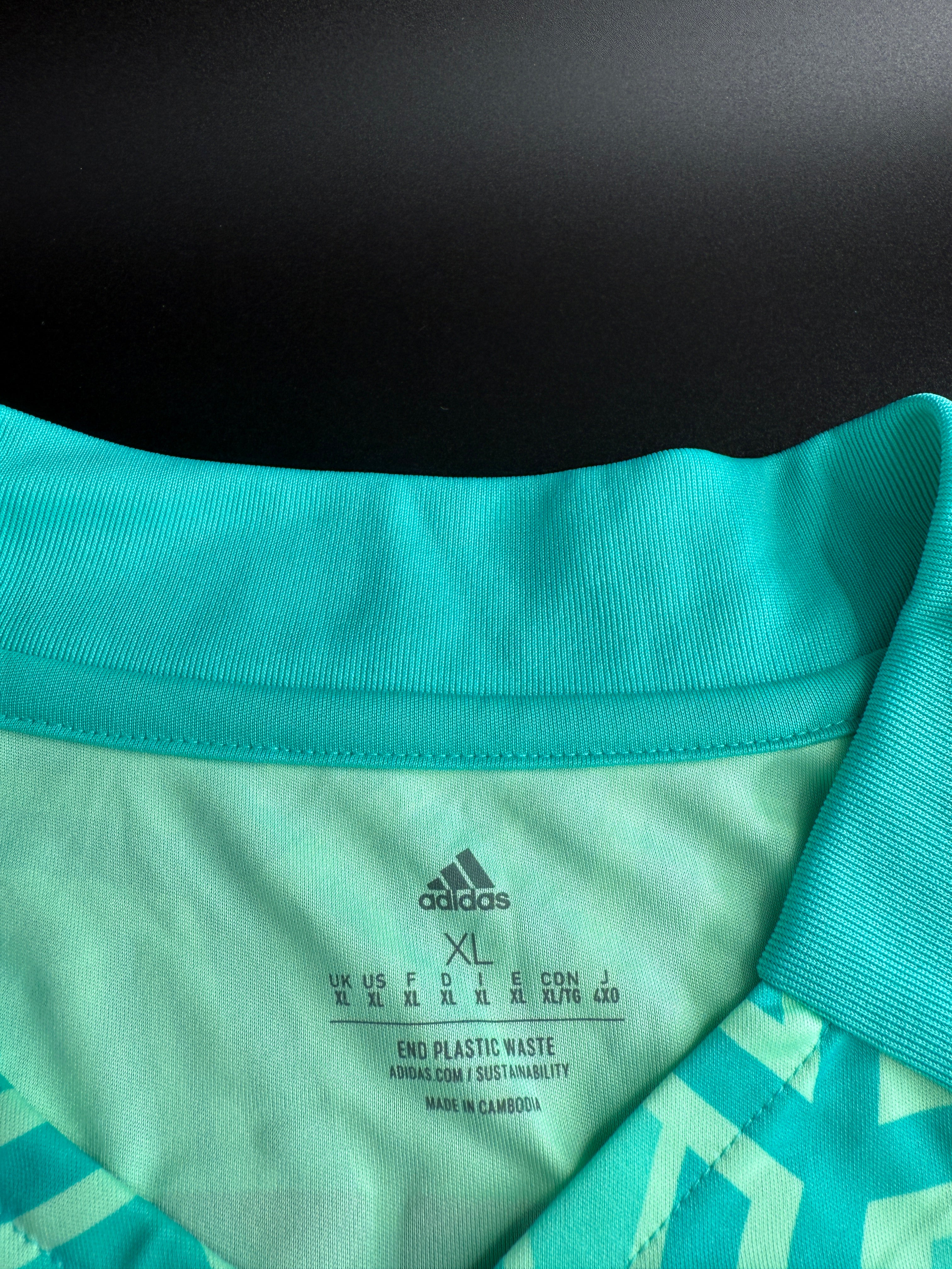 Close-up of teal sports jersey with branding and size details.