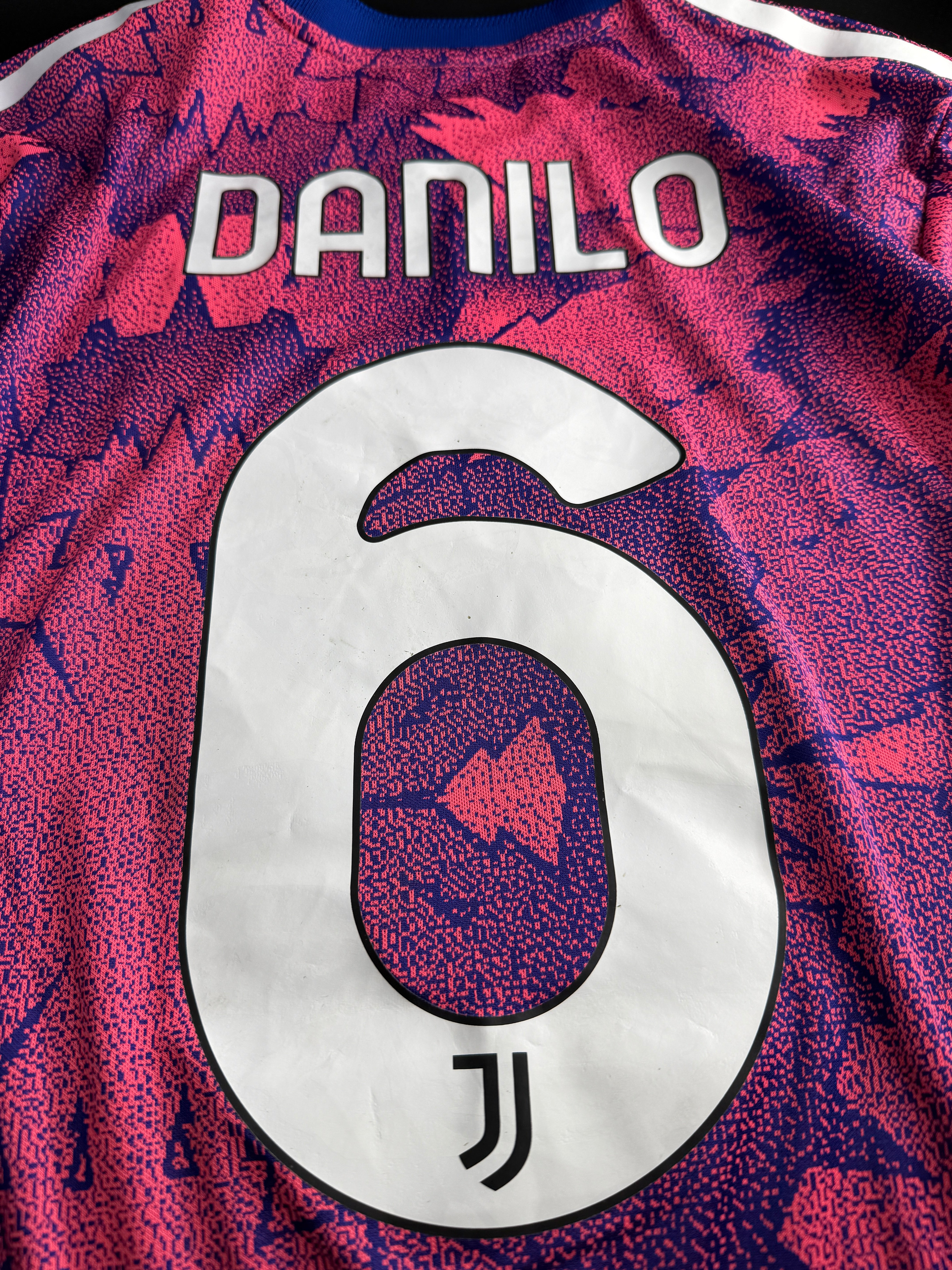 Close-up of a sports jersey with a logo and text on a colorful background.