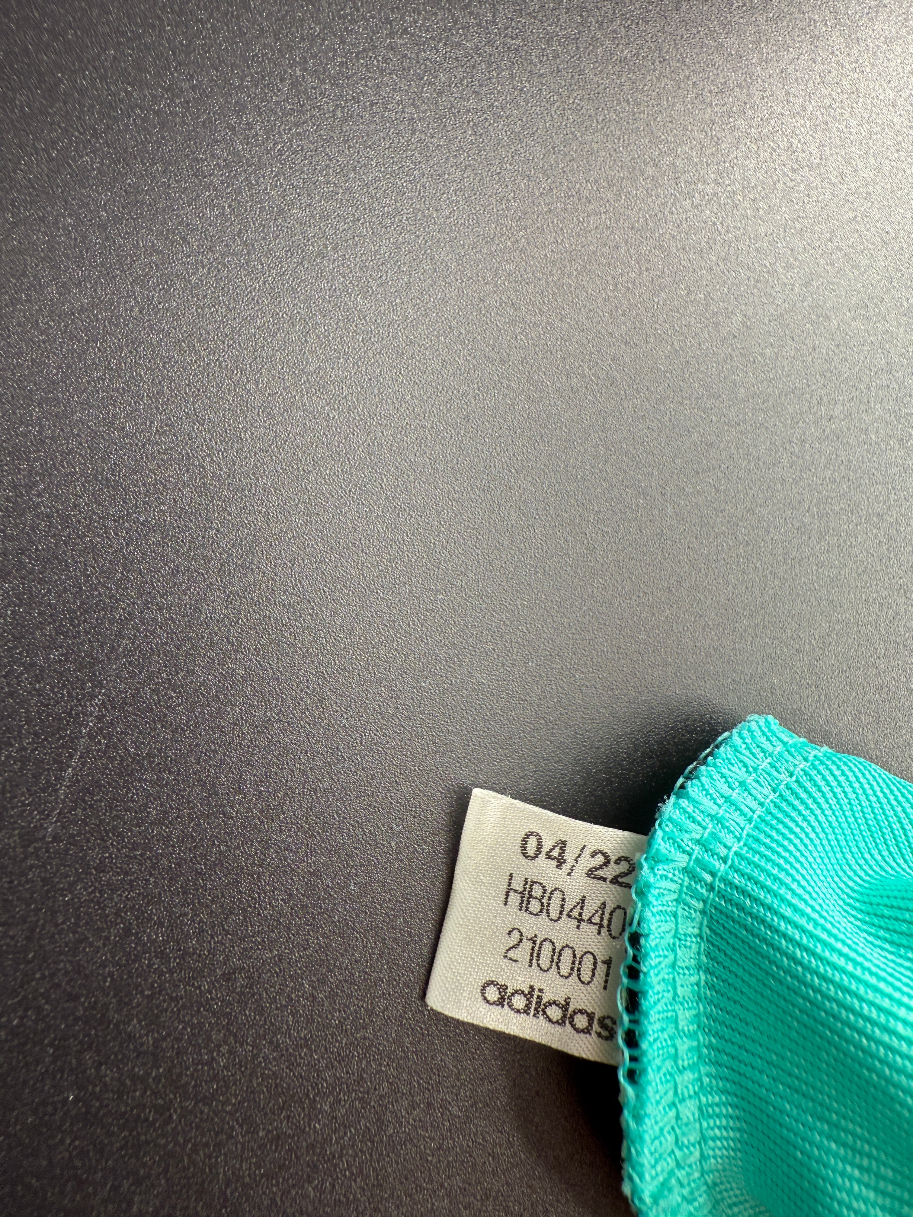 Close-up of a teal fabric tag on a dark surface.
